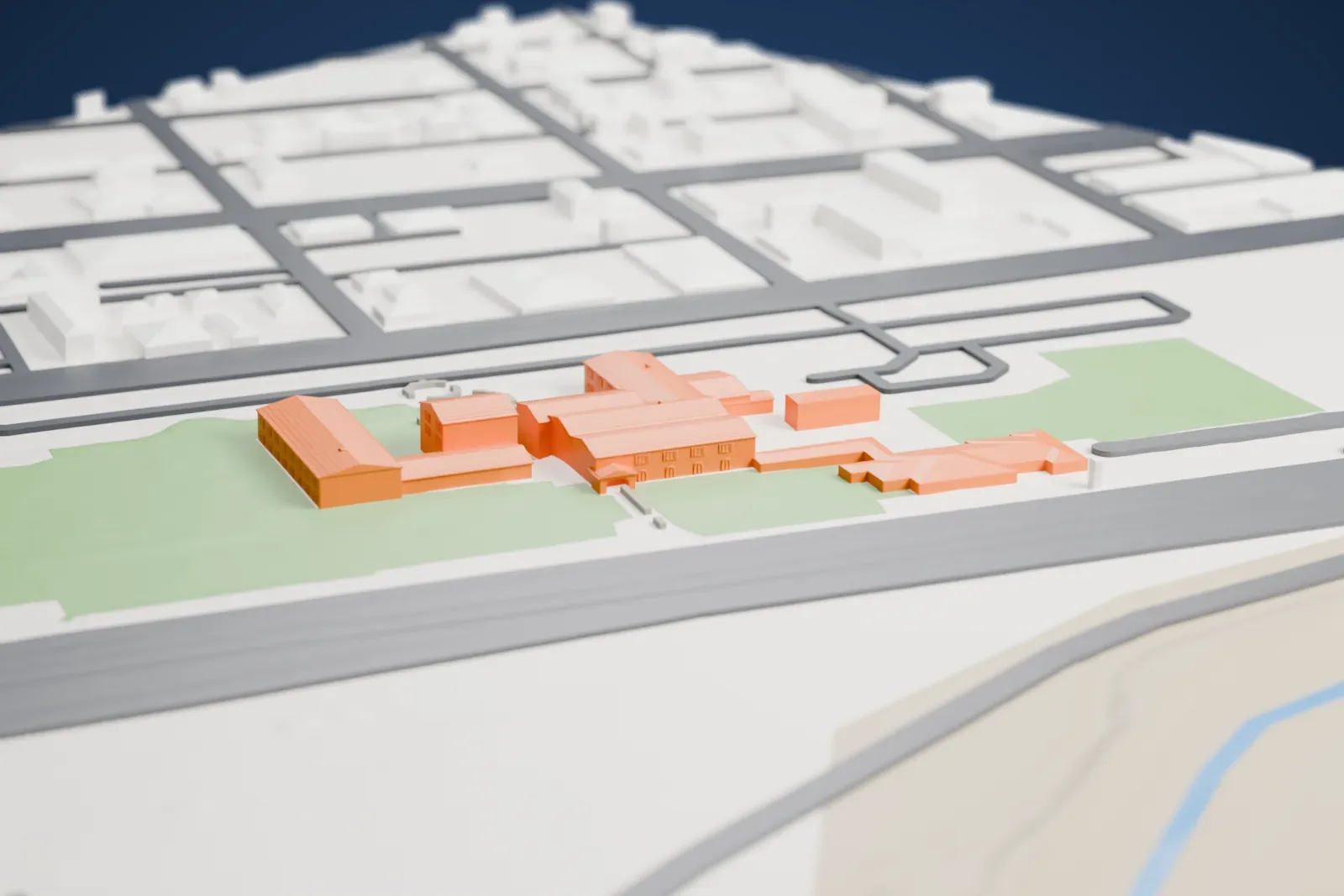 A white 3D print of La Posada Hotel, a group of low connected wings with shallow roofs on green lawns, beside a wide road with small houses nearby.