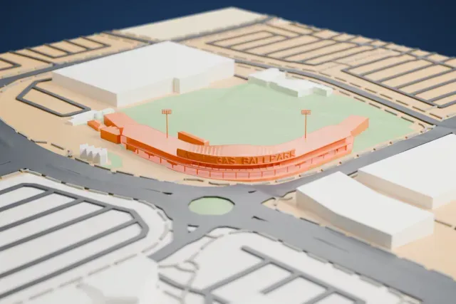 A white 3D print of Las Vegas Ballpark, a baseball field with thin curved grandstand roofs and tall floodlight poles, surrounded by roads and large flat buildings.