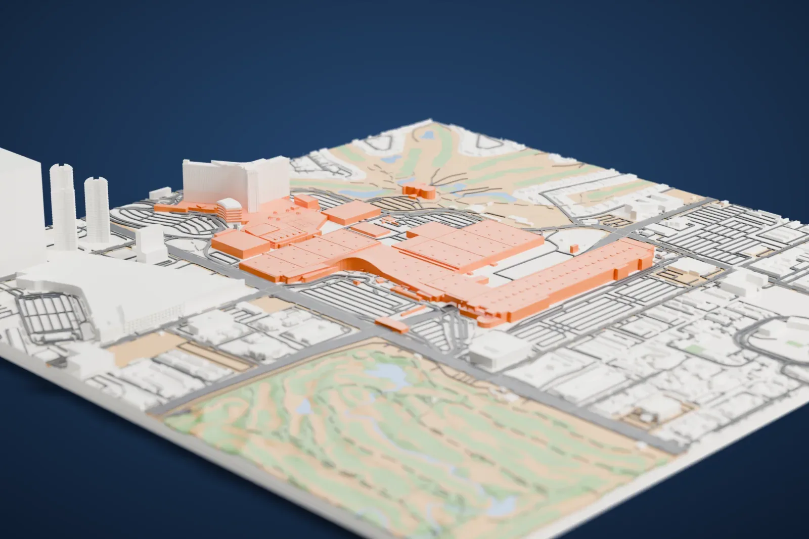 A white 3D print of the Las Vegas Convention Center, a cluster of long, low flat-roofed halls joined by a curved connector, with roads and other buildings around it.