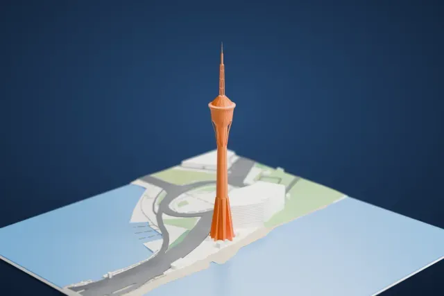 A white 3D print of the Macau Tower, a very tall slender tower with a pod near the top and a thin mast above, standing by the shore among roads, a roundabout and open water.