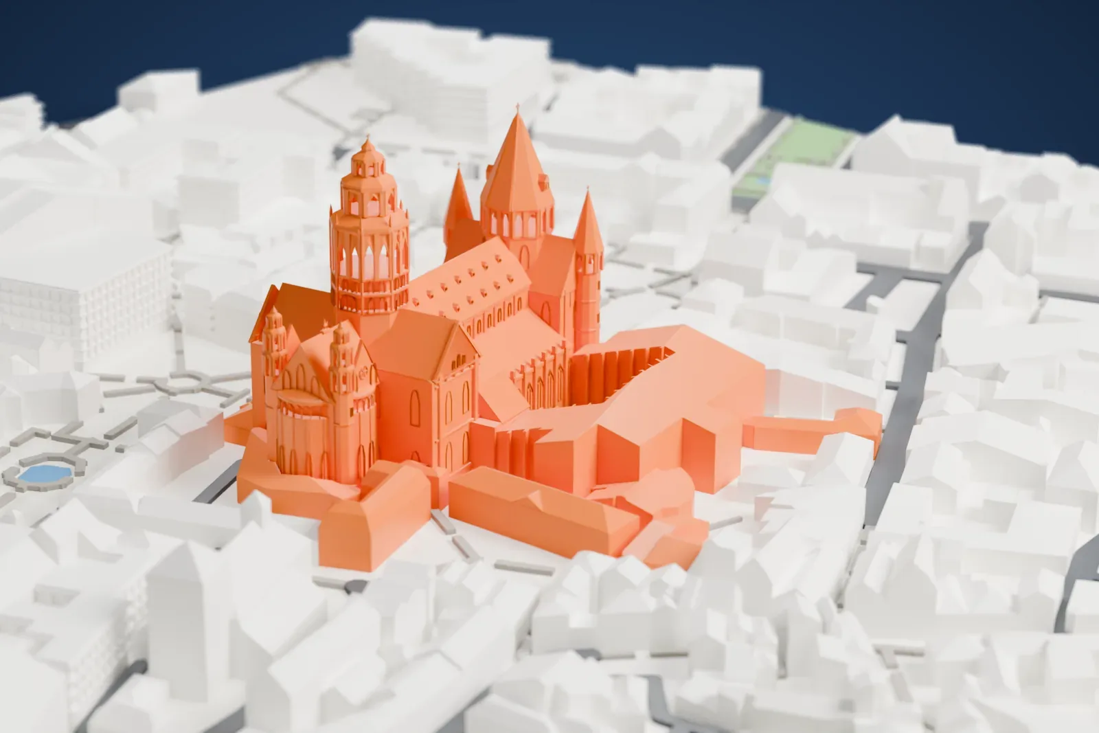 A white 3D print of Mainz Cathedral, a long church with an octagonal crossing tower and tall cone-roofed towers, surrounded by the closely packed buildings and streets of the old town.