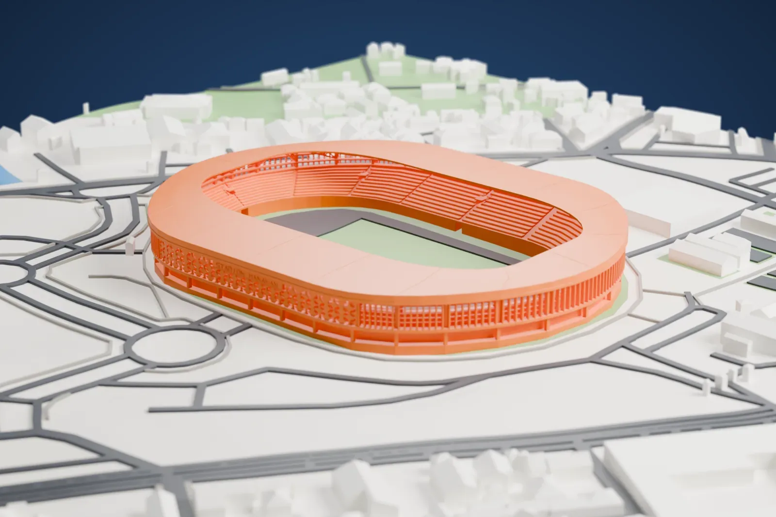 A white 3D print of Manahan Stadium, a large oval stadium with a broad shallow roof and an open pitch, among surrounding roads, roundabouts and low buildings.