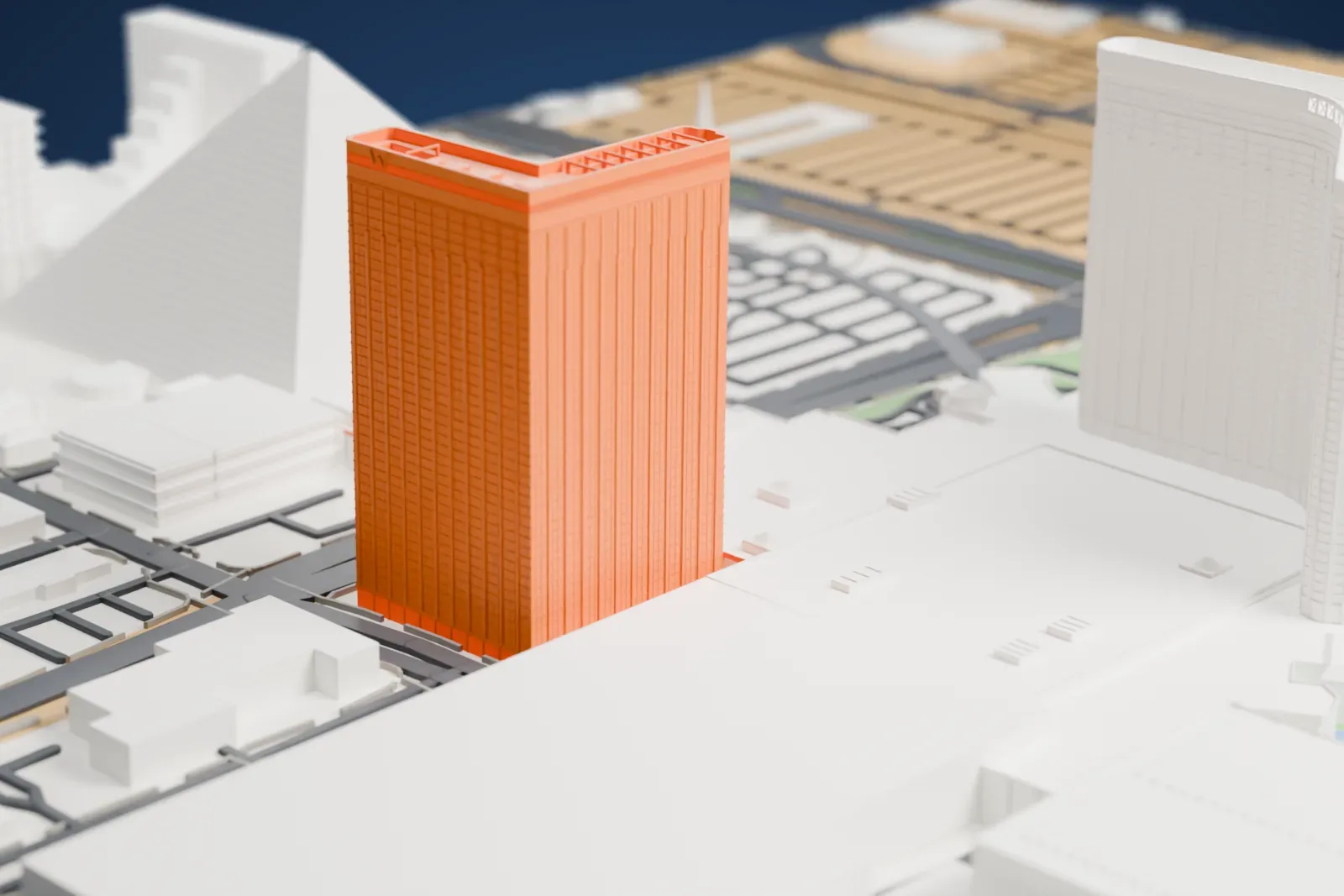 A white 3D print of Mandalay Bay, a curved hotel tower with a slimmer tower and low wings beside it, standing among wide roads and large buildings, with a pyramid-shaped building next to it.