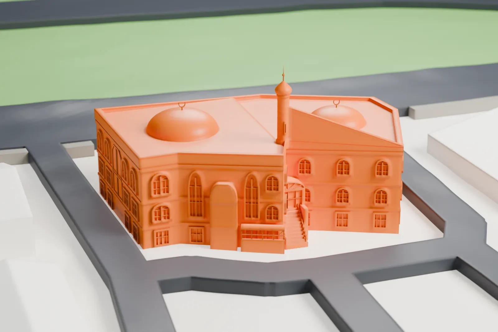 A white 3D print of Masjid Hamza, a three-story building with two low domes and a slim tower, standing on its own block beside streets.