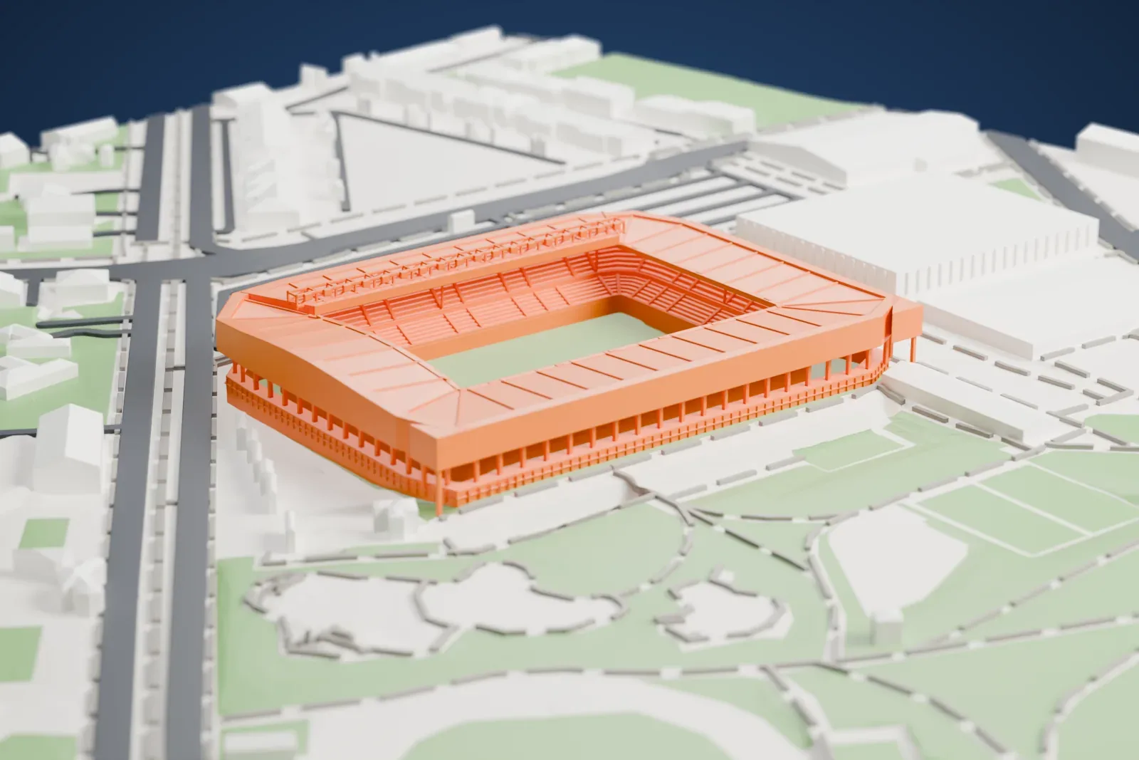 A white 3D print of Mendizorrotza Stadium, a closed rectangular bowl with roofs over all four sides and a scoreboard in the west fascia, among the streets and buildings around it.