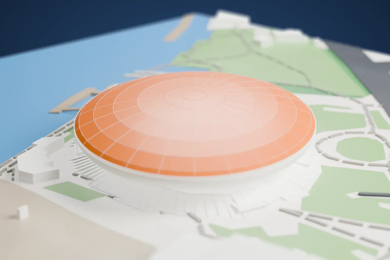 A white 3D print of the Mercedes-Benz Arena, a wide saucer-shaped domed arena ringed by low stepped details, with park paths, open ground and the water's edge around it.