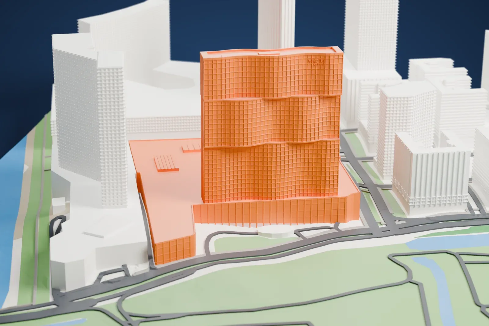 A white 3D print of MGM Macau, with three curved stacked slabs above a broad podium, among surrounding streets and buildings.