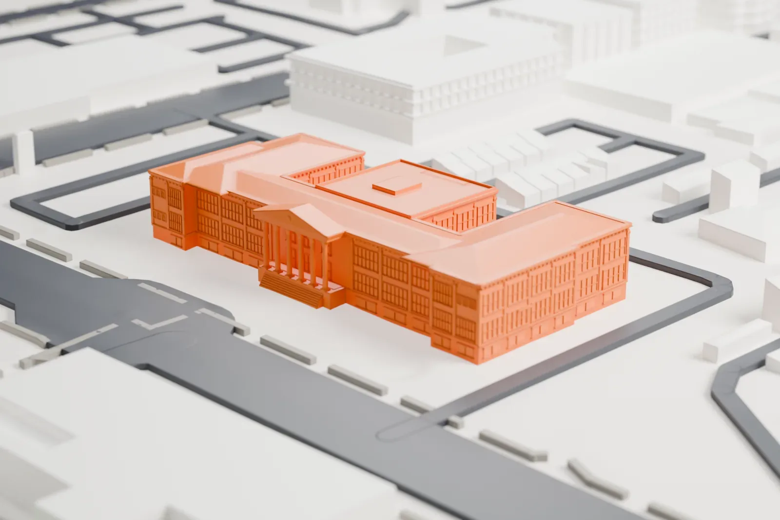 A white 3D print of the Monroe School, a building with a columned front entrance and several hipped roofs, surrounded by streets and low buildings.