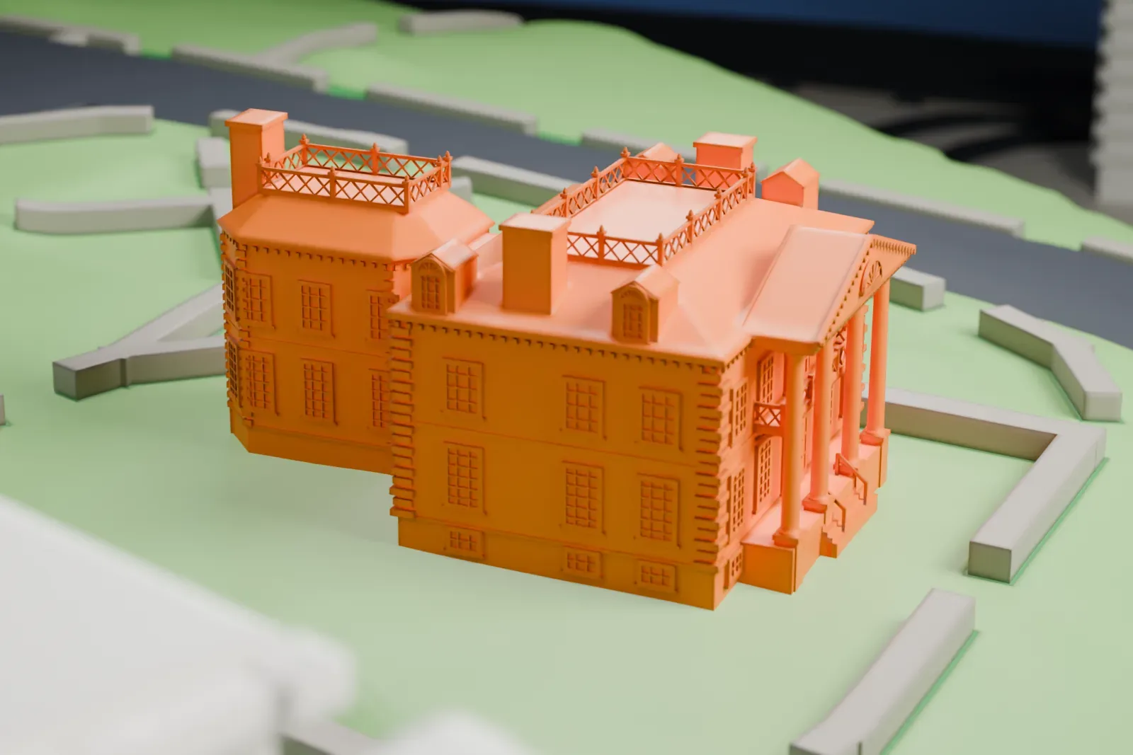 A white 3D print of the Morris–Jumel Mansion, a wooden-style house with a columned front and an octagonal wing, standing on a green lawn ringed by paths.
