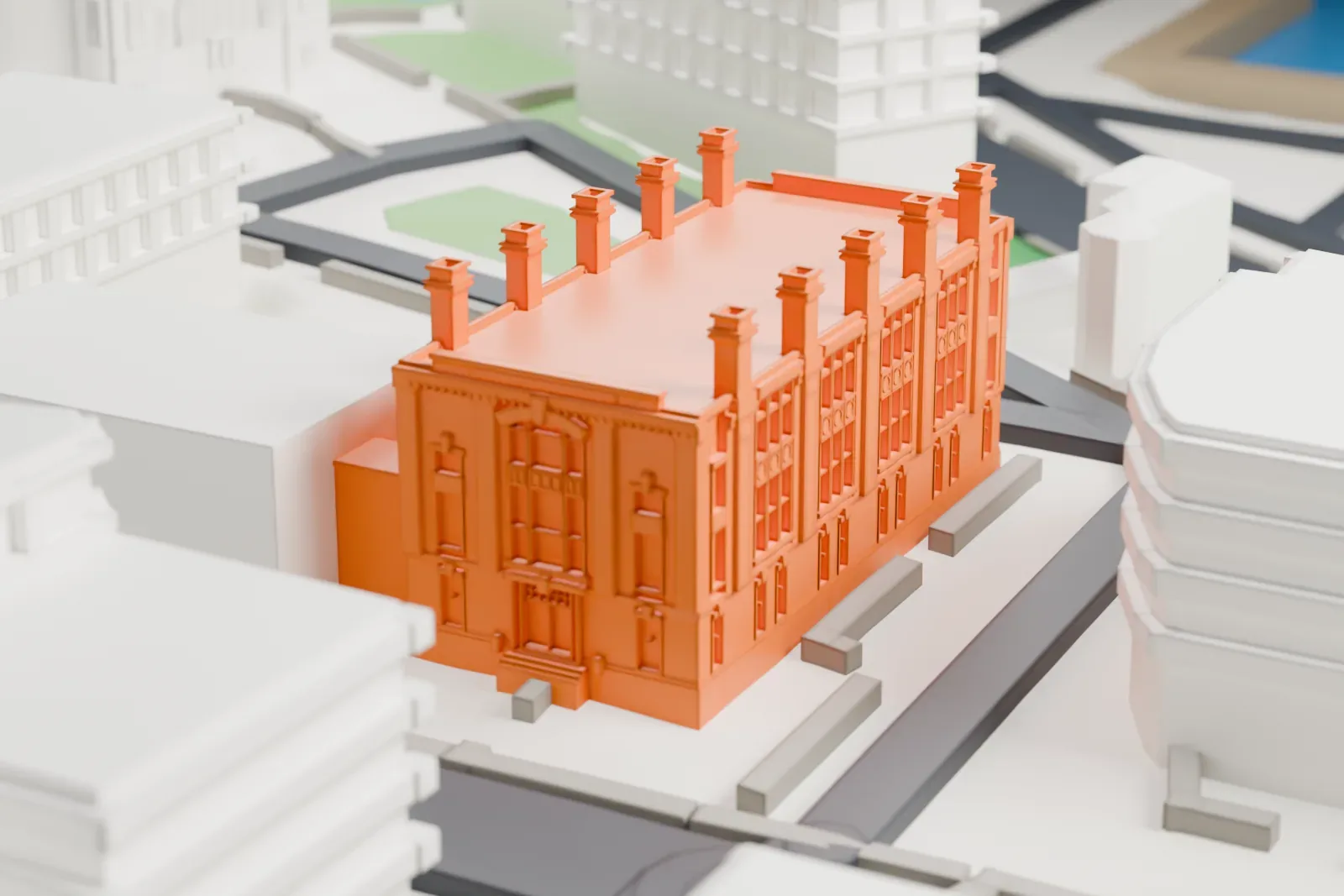 A white 3D print of a rectangular laboratory building with a row of small chimneys along its roof, among taller buildings and streets.