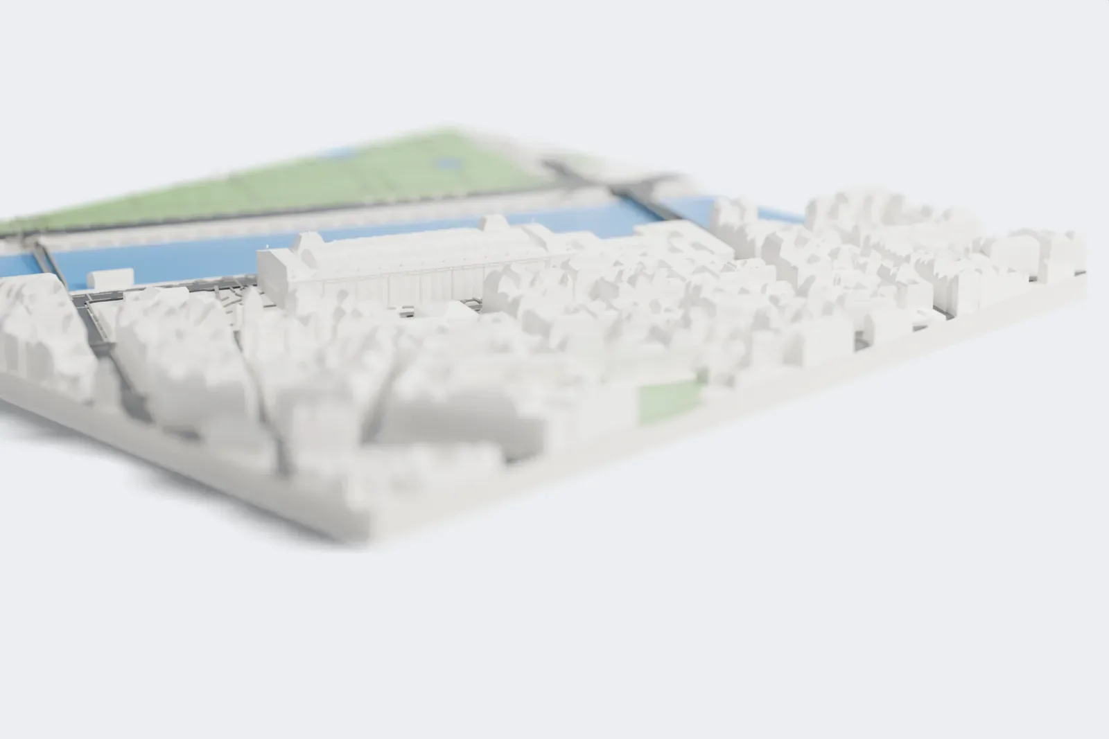 A white 3D print of the Musée d'Orsay, a long building with a curved ribbed roof and arched windows, beside a wide river with streets and buildings around it.