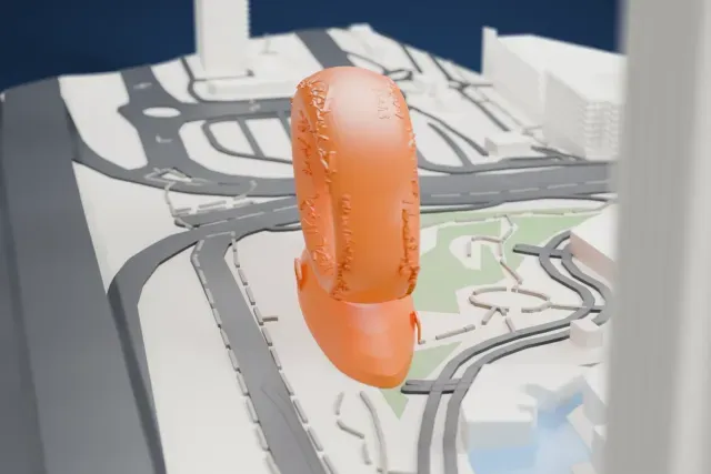 A white 3D print of the Museum of the Future, an oval ring covered in raised calligraphy standing on a wide elliptical base, with roads, small green patches and tall towers nearby.