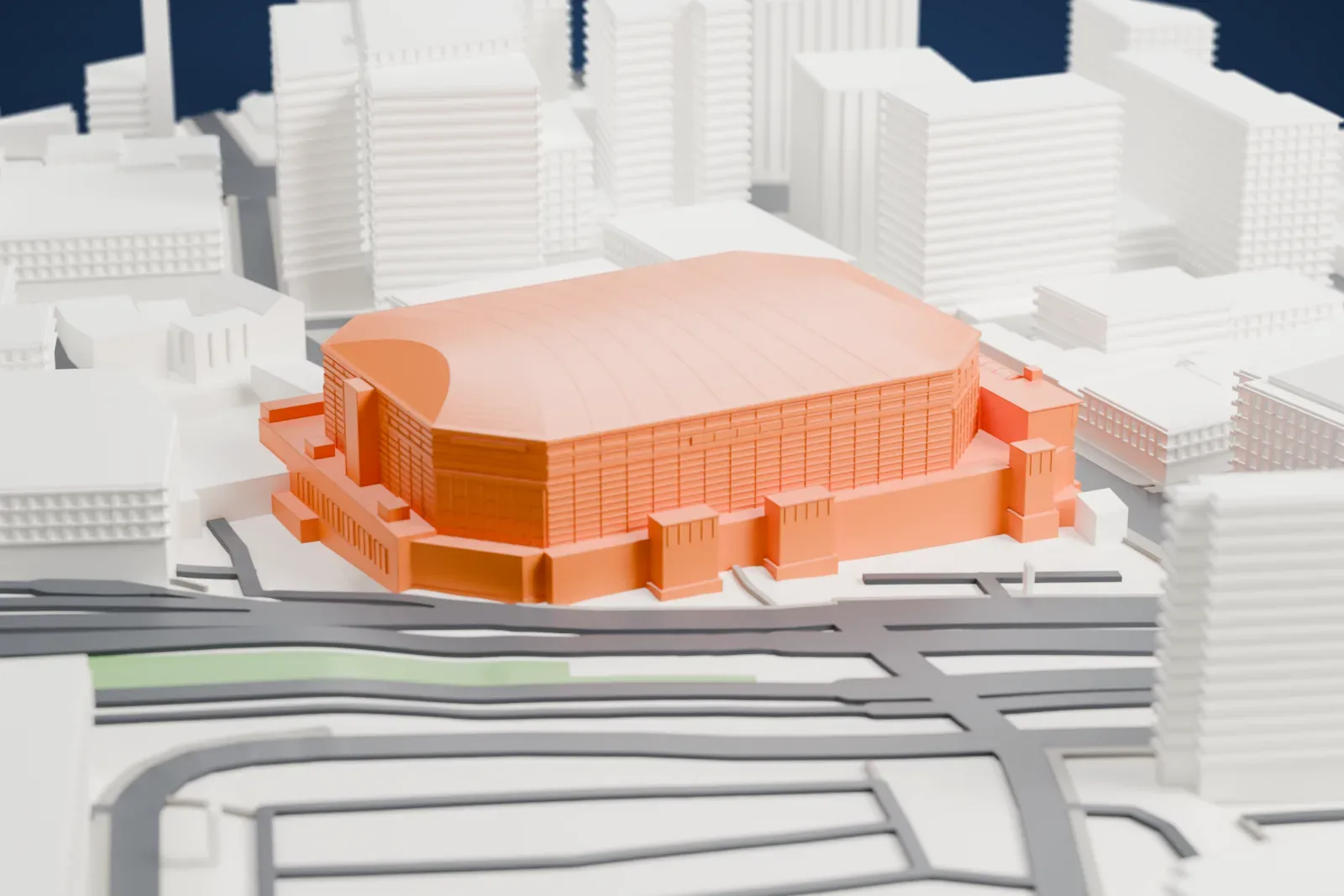 A white 3D print of MVP Arena, a long arena with a shallow barrel roof and glazed corners, among the streets and buildings of Albany.