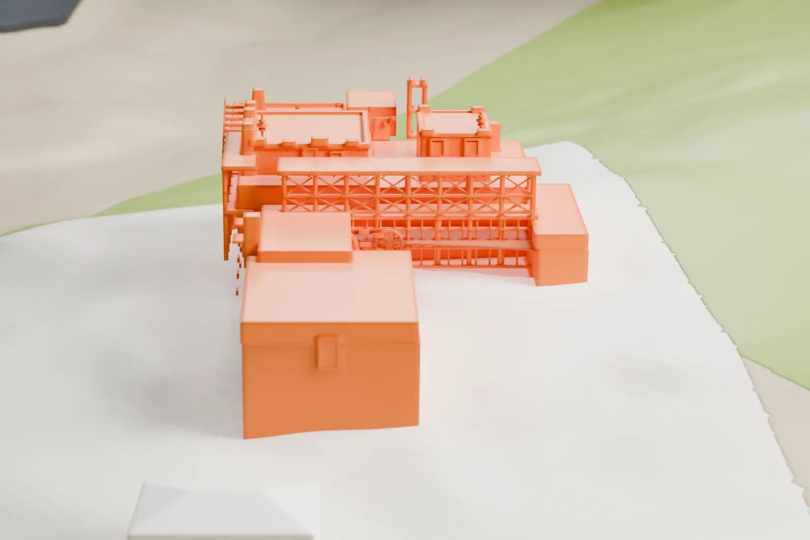 A white 3D print of the Mystery Castle house with stepped flat roofs and thin railings, on sloping ground beside a small building and open green areas.