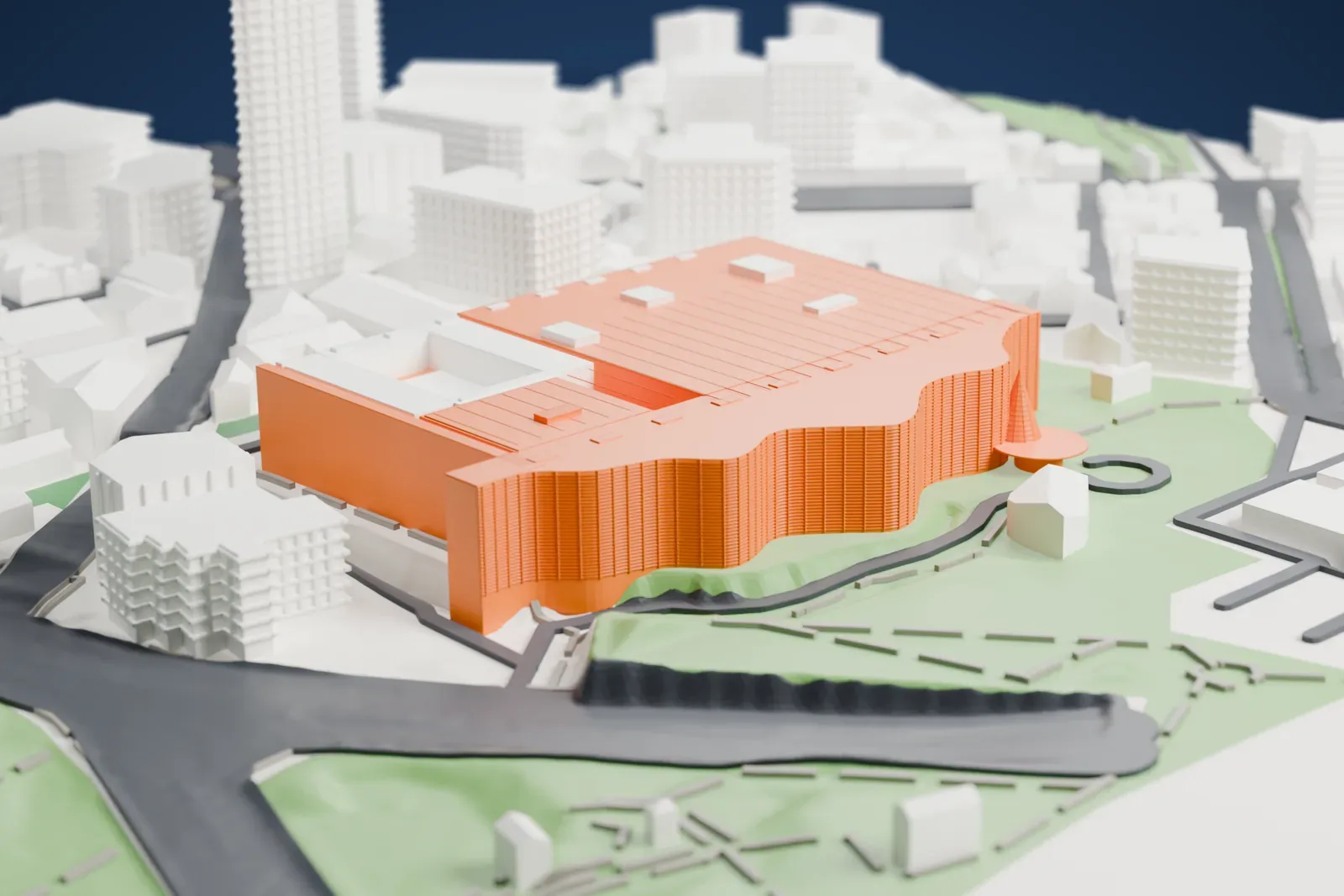 A white 3D print of the National Art Center, Tokyo, a wide low building with a wavy curved front, a flat roof and a cone on a round base, surrounded by streets, green space and smaller buildings.