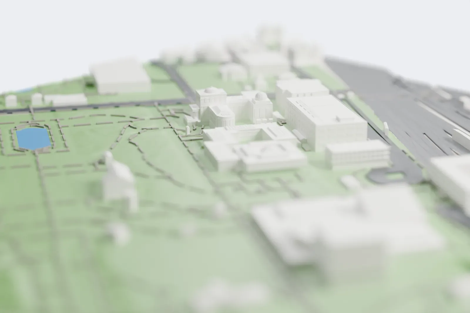 A white 3D print of the National Museum of Western Art, a low square building around an open courtyard with a small pyramid on its roof, among park lawns and paths.