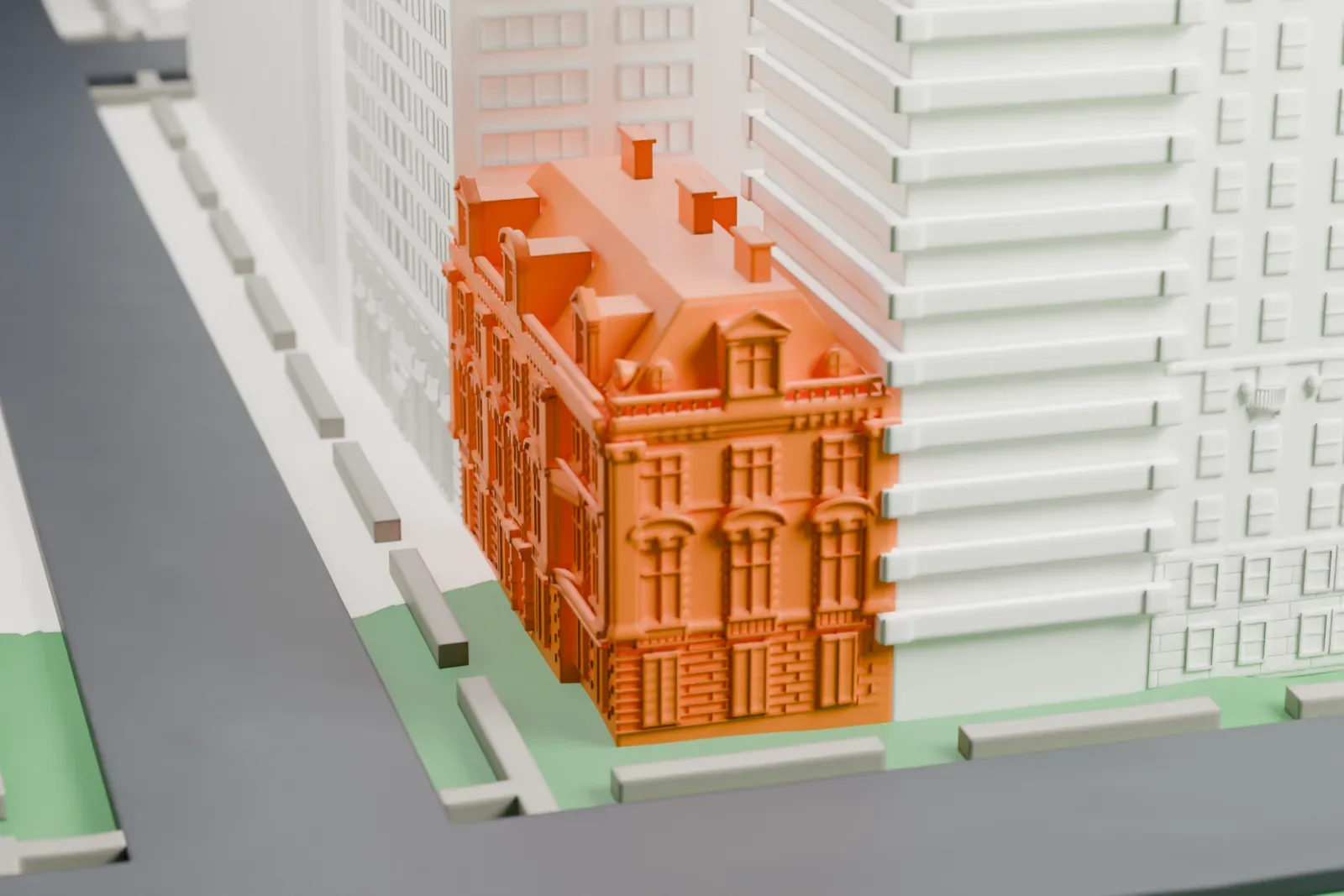 A white 3D print of the Neue Galerie New York, an ornate corner house with a mansard roof, standing beside a street and much taller buildings.