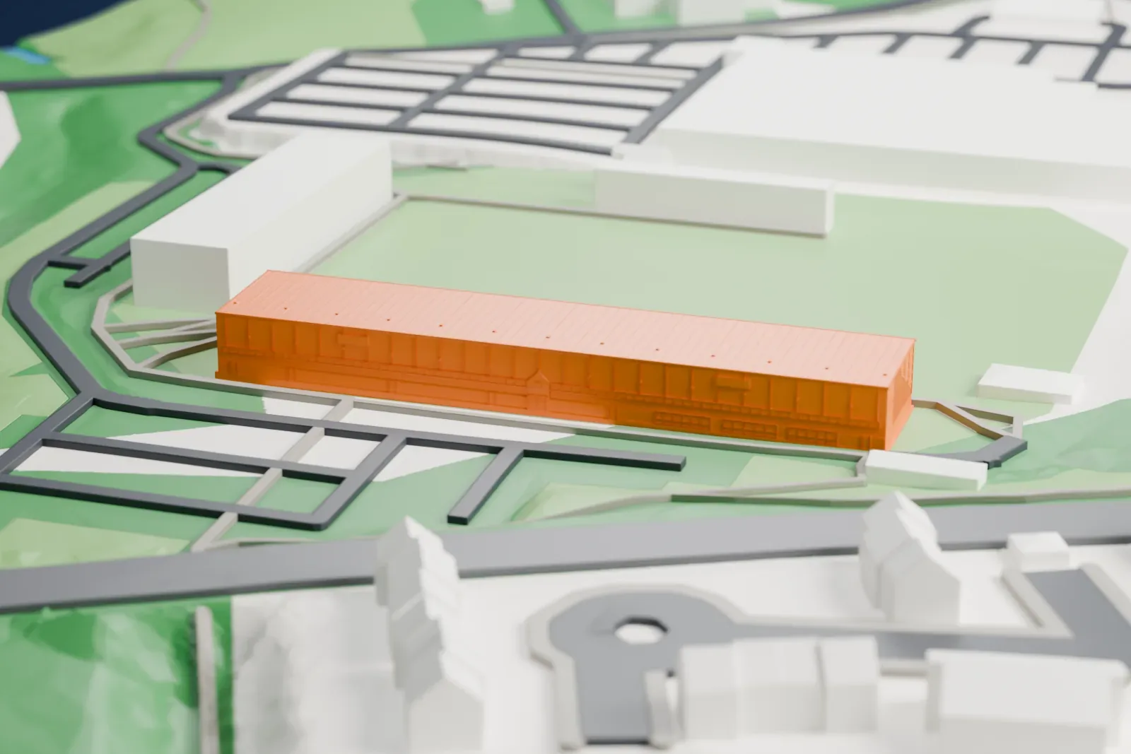 A white 3D print of New Douglas Park's main stand, with its long shallow roof and open seating rake among the surrounding streets and buildings.