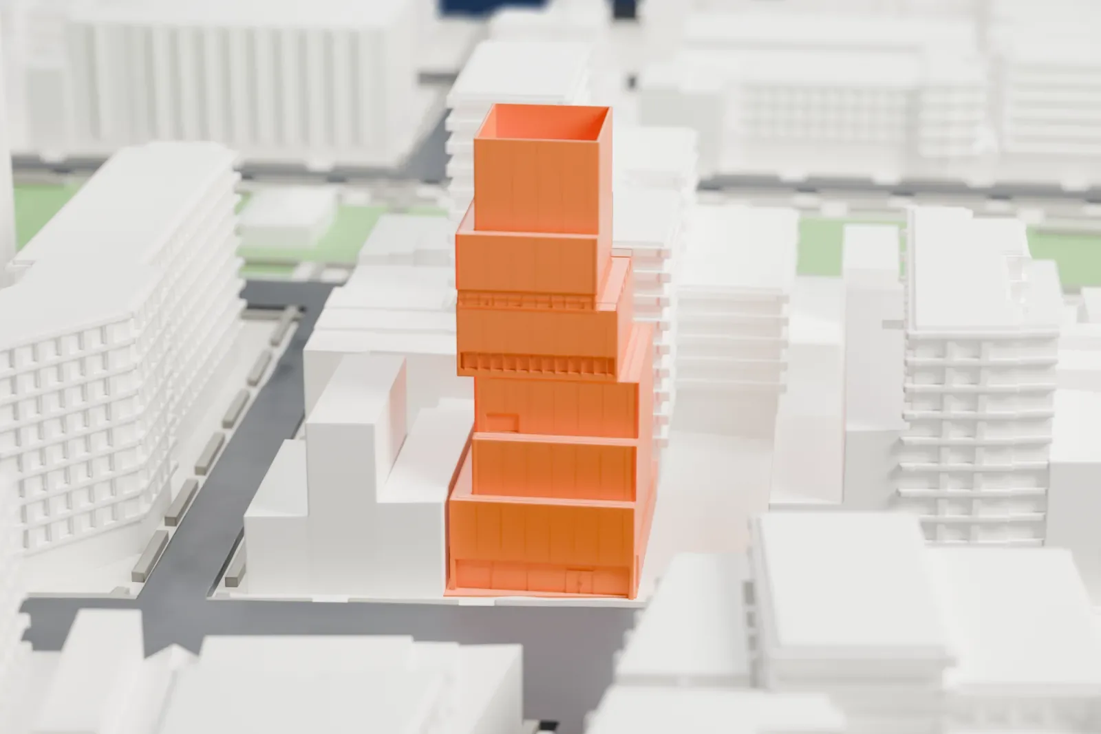 A white 3D print of the New Museum, a tall stack of offset rectangular boxes rising between mid-rise buildings on a street in Manhattan.