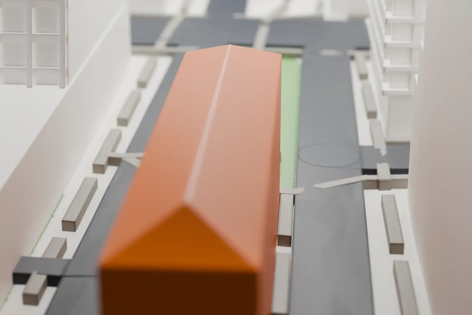 A white 3D print of the New York City Police Museum building, a long arched-window palazzo with a hipped roof, beside a street, a small plaza and much taller towers.