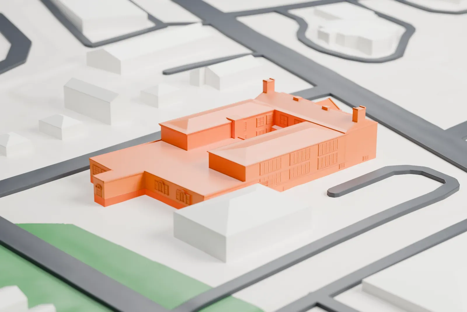 A white 3D print of the North Main Street School, a long brick school with wings around a courtyard, on a lot between streets with smaller houses nearby.
