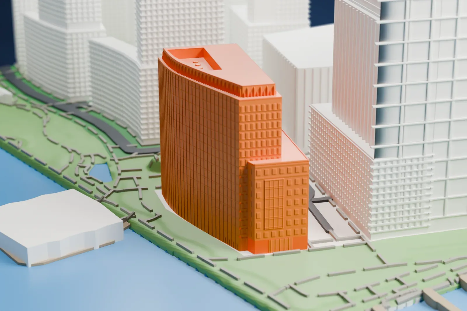 A white 3D print of One North End Avenue, a tall building with a curved side and a stepped top, standing at the water's edge beside a green strip.