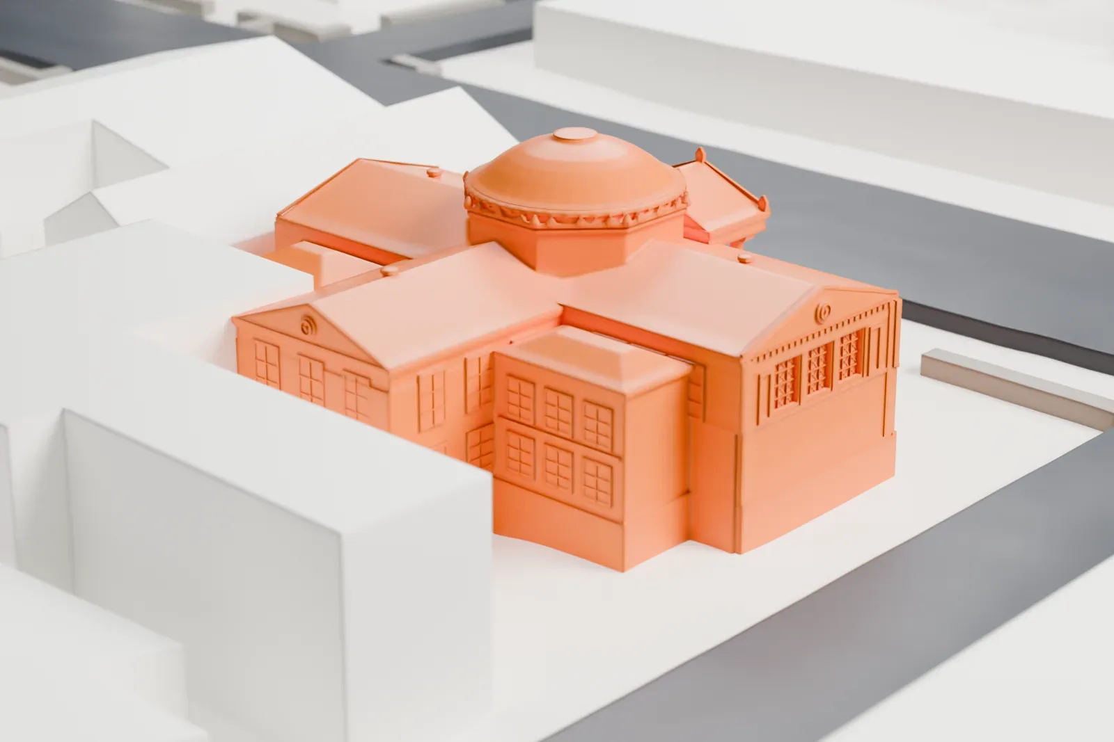 A white 3D print of the Orange Public Library, a building with a central dome, a columned entrance and hipped roofs, on a street corner among taller buildings.