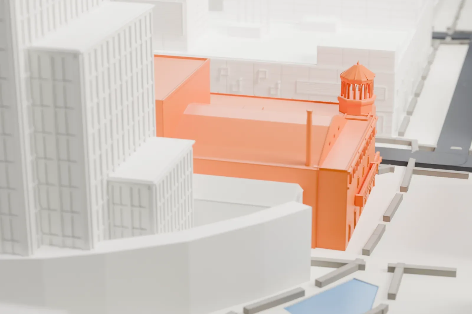 A white 3D print of the Orpheum Theatre, a low building with a small domed turret, tucked between much taller downtown buildings, streets and a plaza.