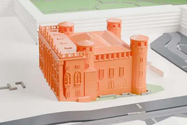 A white 3D print of Palazzo Madama, a square palace with four round corner towers and a columned front, standing in an open plaza with streets and larger buildings around it.