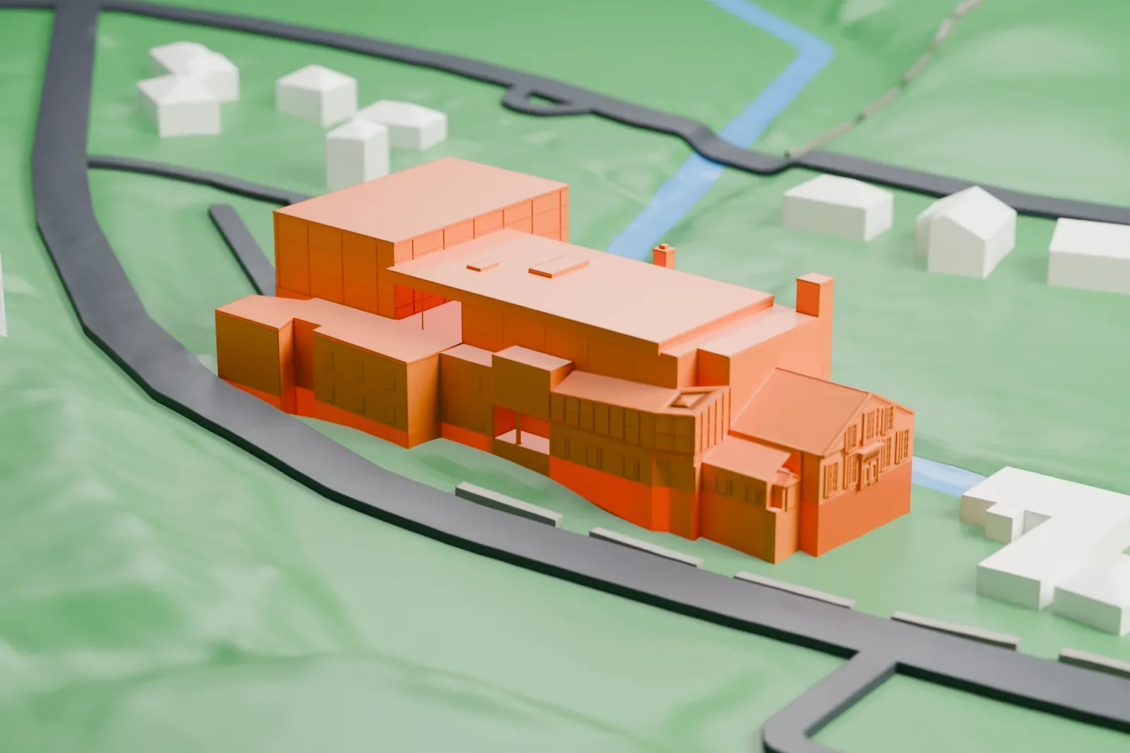 A white 3D print of Paper Mill Playhouse, a cluster of stepped blocks on green ground beside a curving river, with small houses nearby.