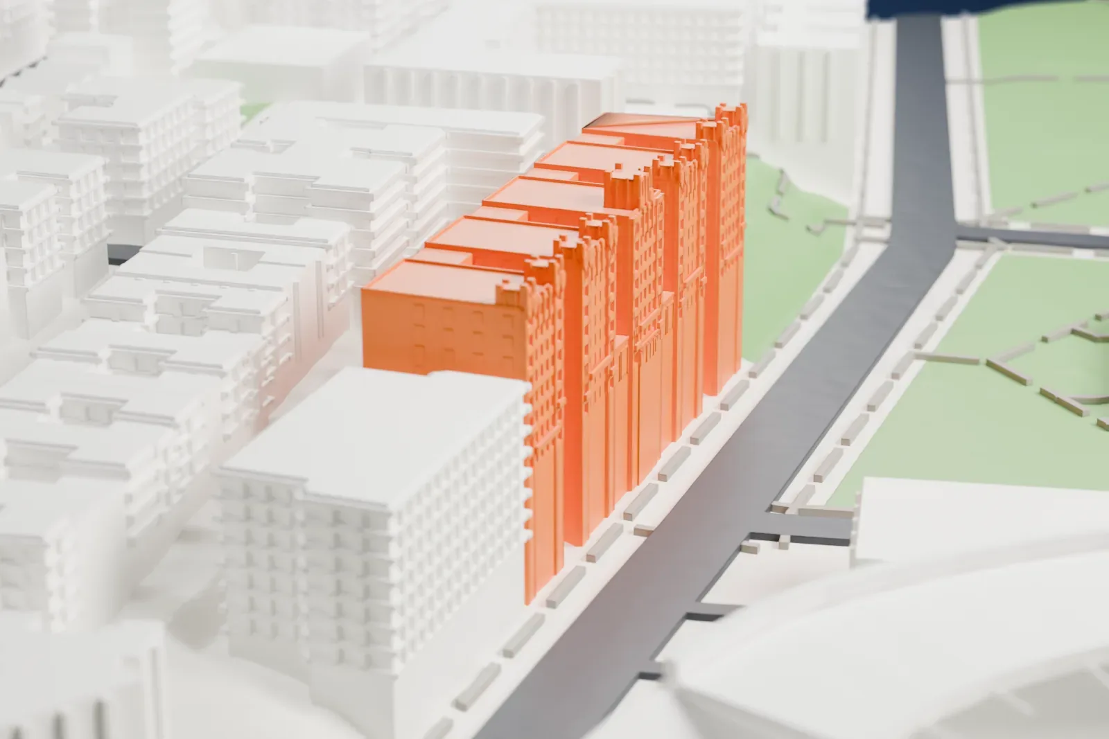 A white 3D print of the Park Plaza Apartments, a long eight-story building made of five stepped sections, beside a green park and a street.