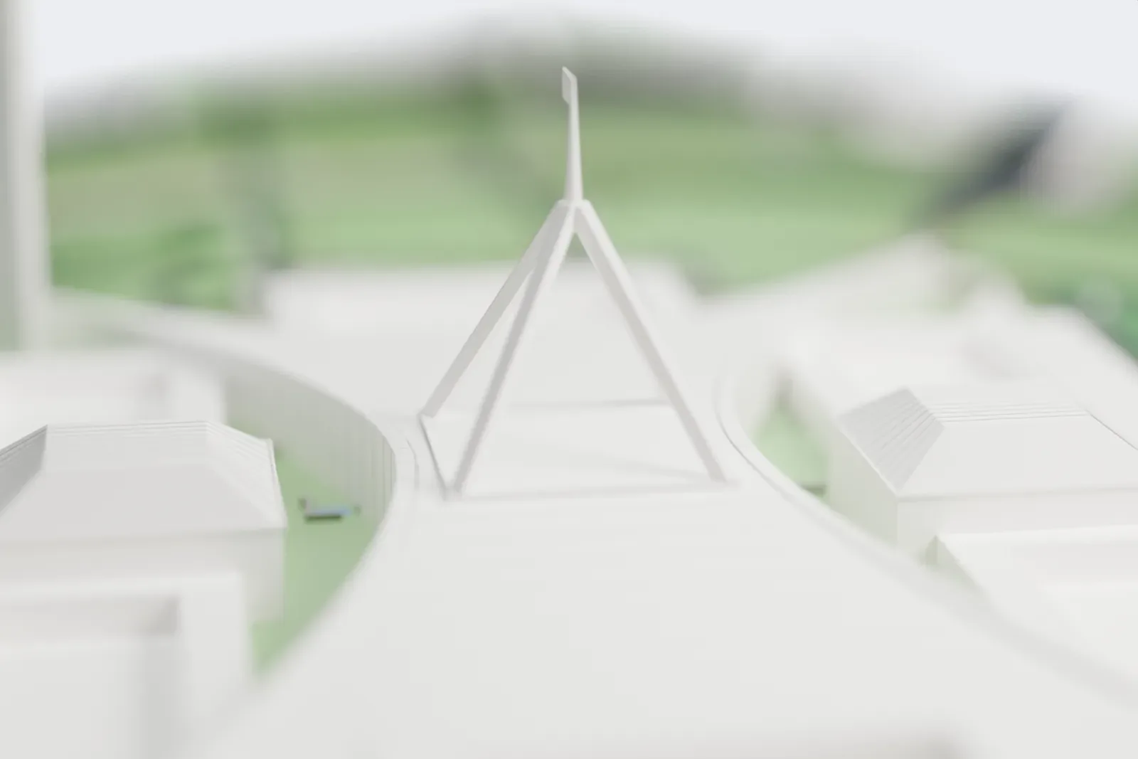 A white 3D print of Parliament House in Canberra, a low, wide building with long curved walls and a tall four-legged flagpole mast, on a hill inside a ring road with parkland around it.