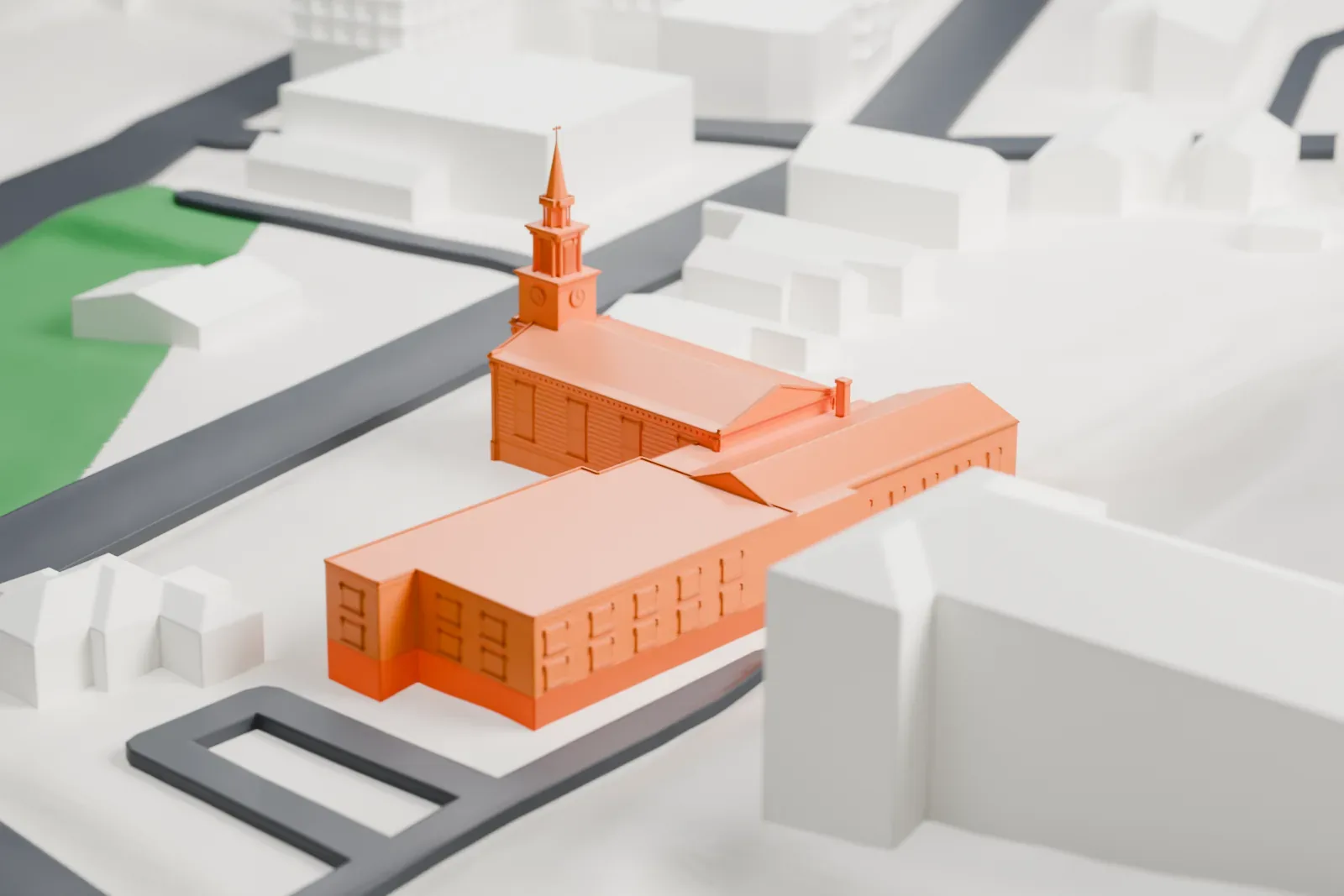 A white 3D print of Peekskill Presbyterian Church, a long gabled church with a steepled bell tower at its front, on open ground near a road with other buildings around it.