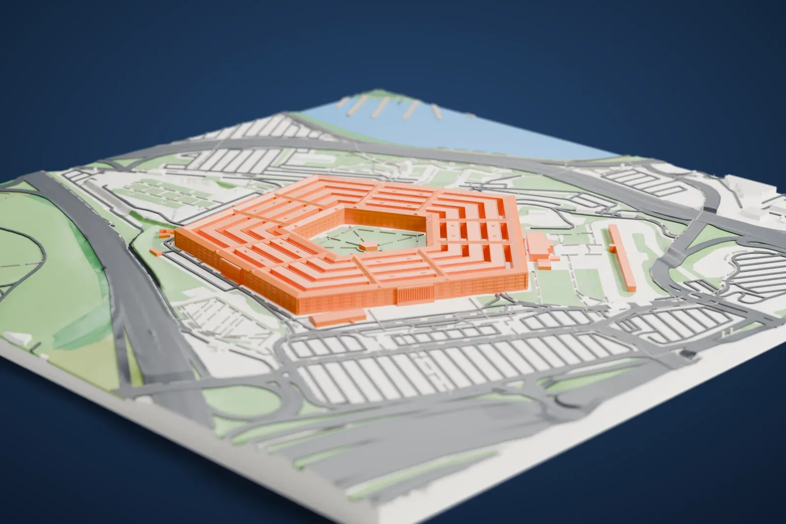 A white 3D print of The Pentagon, a five-sided building of concentric rings around a courtyard, surrounded by parking lots, roads, green lawns and a river nearby.