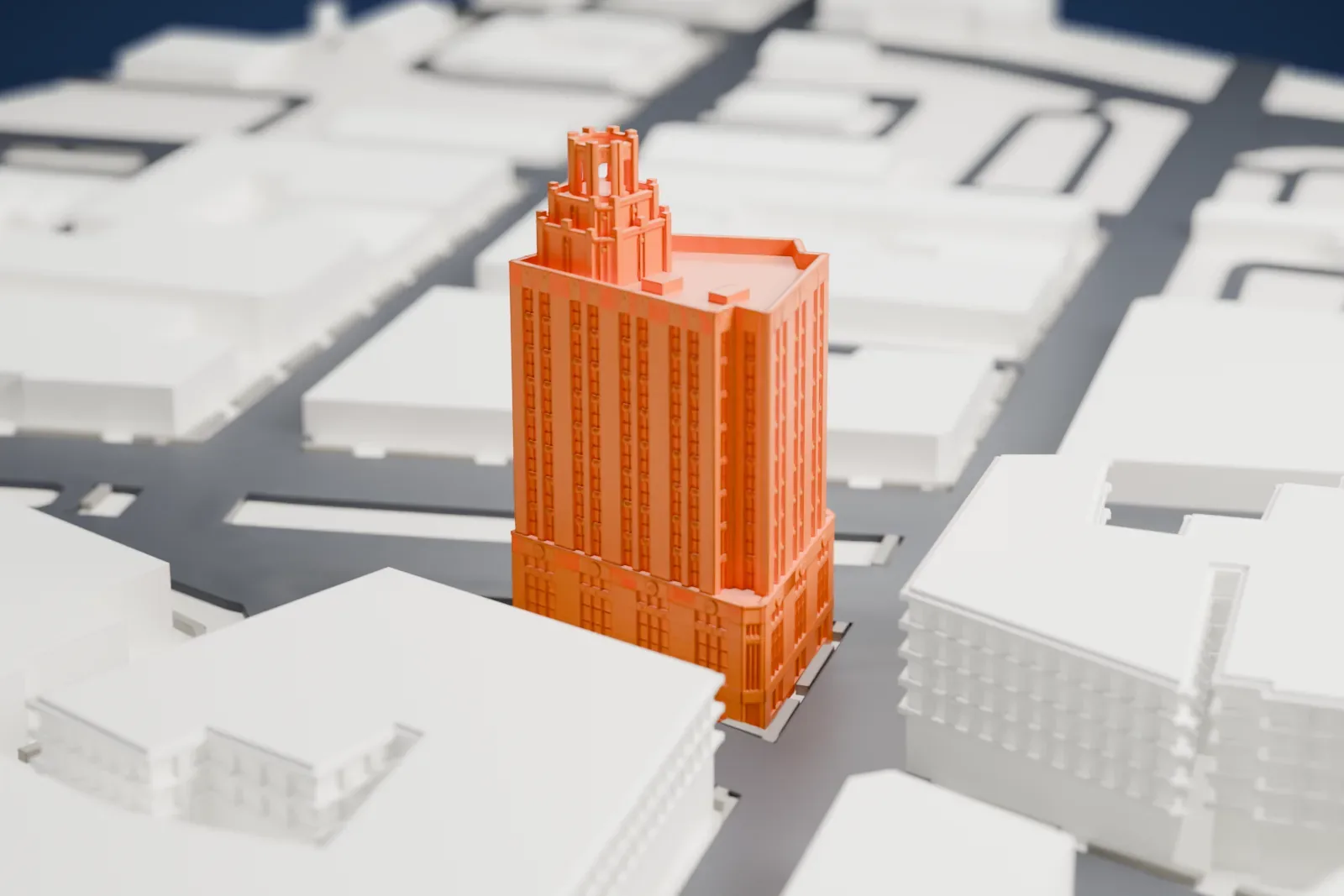 A white 3D print of the People's Bank and Trust Company Building, a tall narrow tower with a stepped crown, on a street corner among lower buildings.