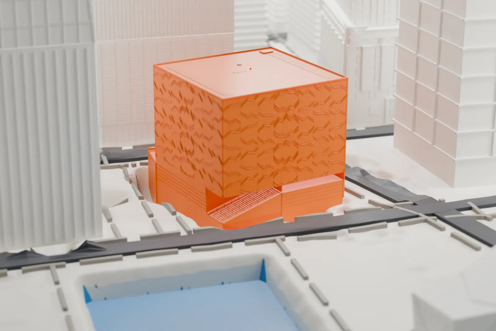 A white 3D print of the Perelman Performing Arts Center, a boxy building with a textured facade, close to a water feature and surrounded by taller buildings.