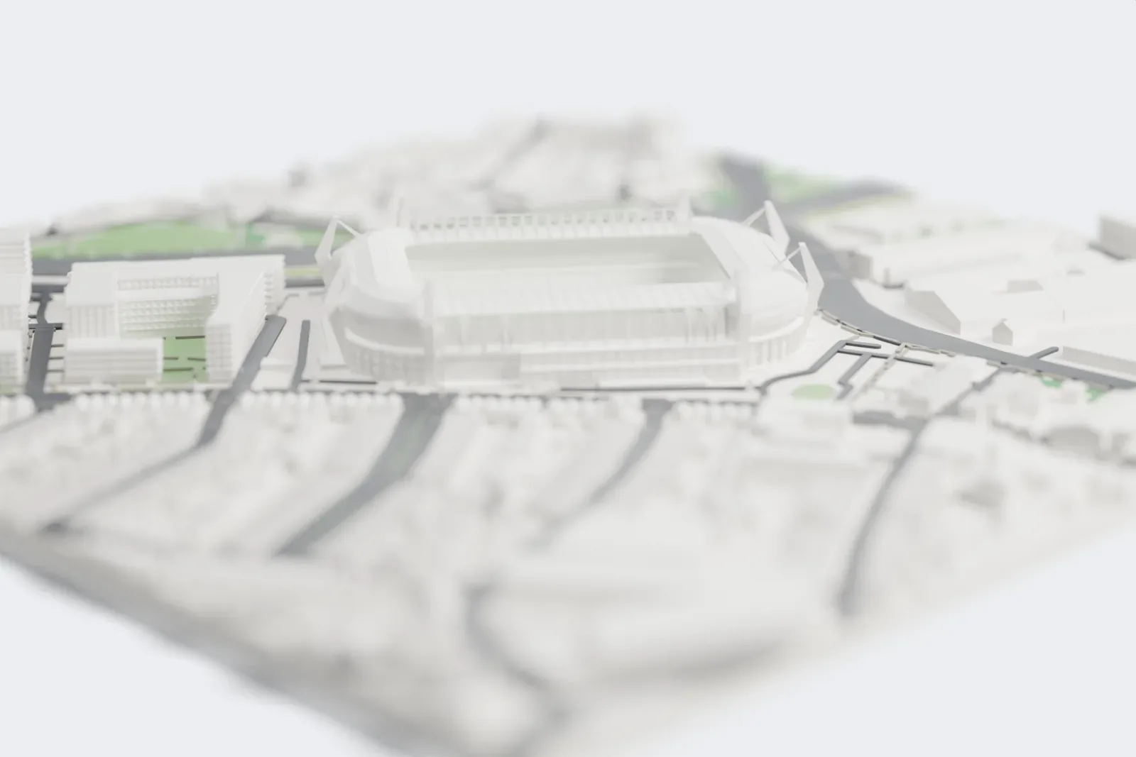 A white 3D print of the Philips Stadion, a rounded rectangular bowl with slanted pylons at its corners and ribbed roofs along the sides, surrounded by streets, wide roads and city buildings.