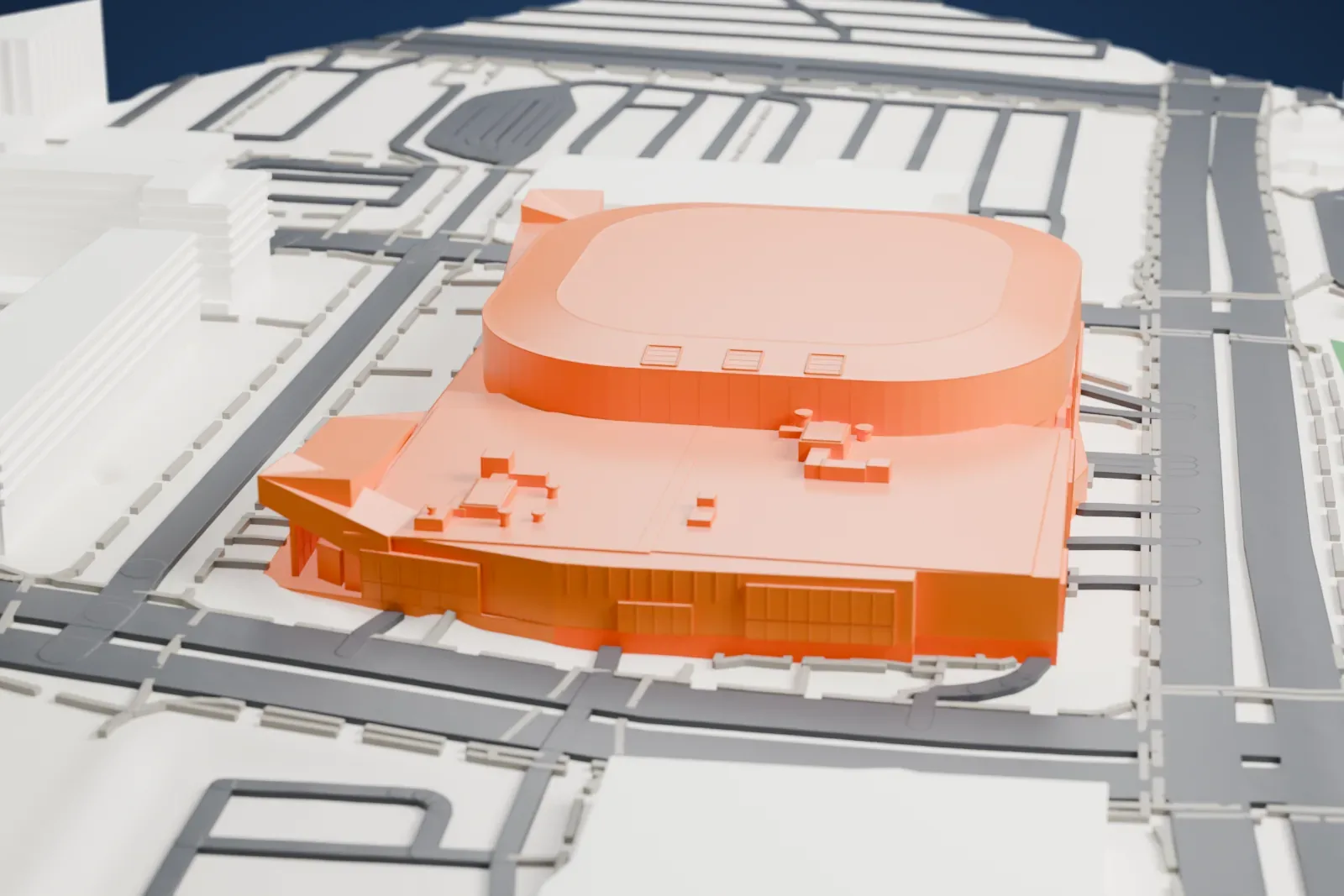 A white 3D print of Place Bell, an oval arena with a lower block beside it, surrounded by wide roads, large low buildings, taller buildings and a patch of green.