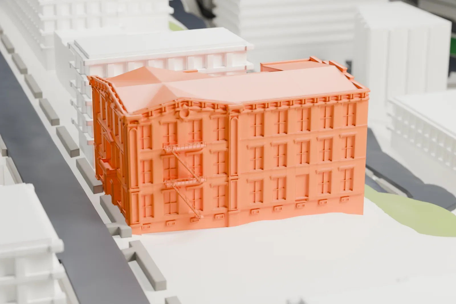 A white 3D print of Pohlmann's Hall, a boxy multi-story building with a trimmed front and a hipped roof, beside a street and neighboring buildings.