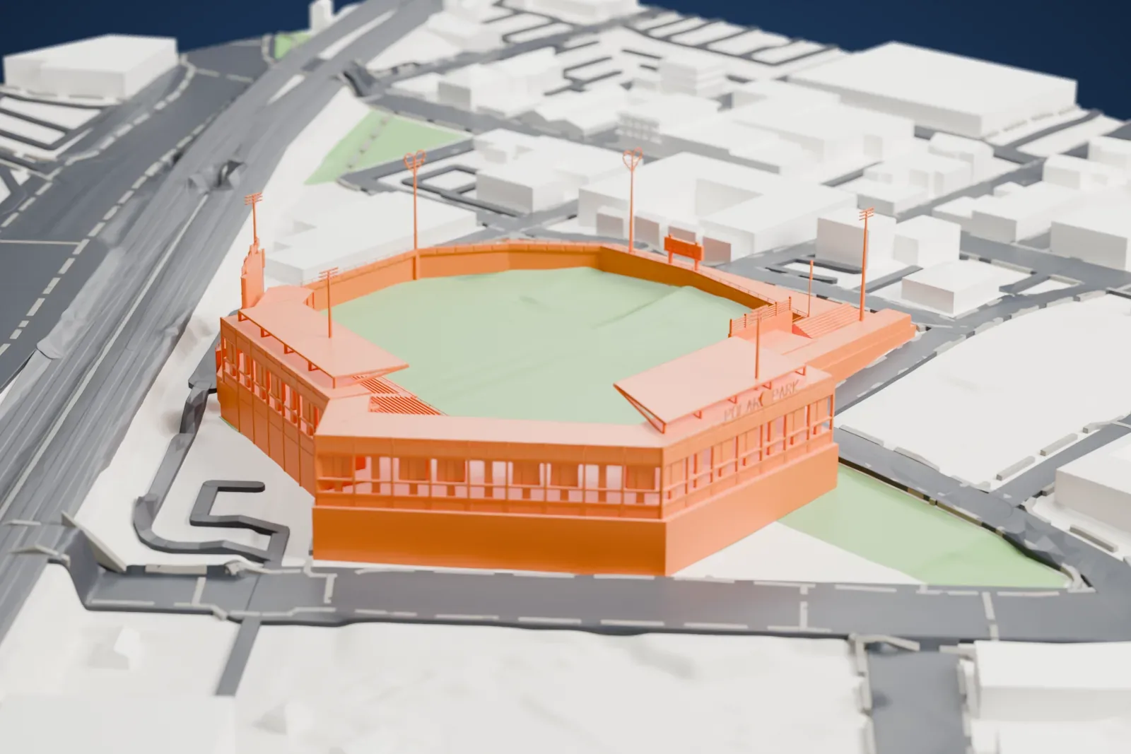 A white 3D print of Polar Park, a ballpark with a curved grandstand around a green field, beside a wide road and city blocks.