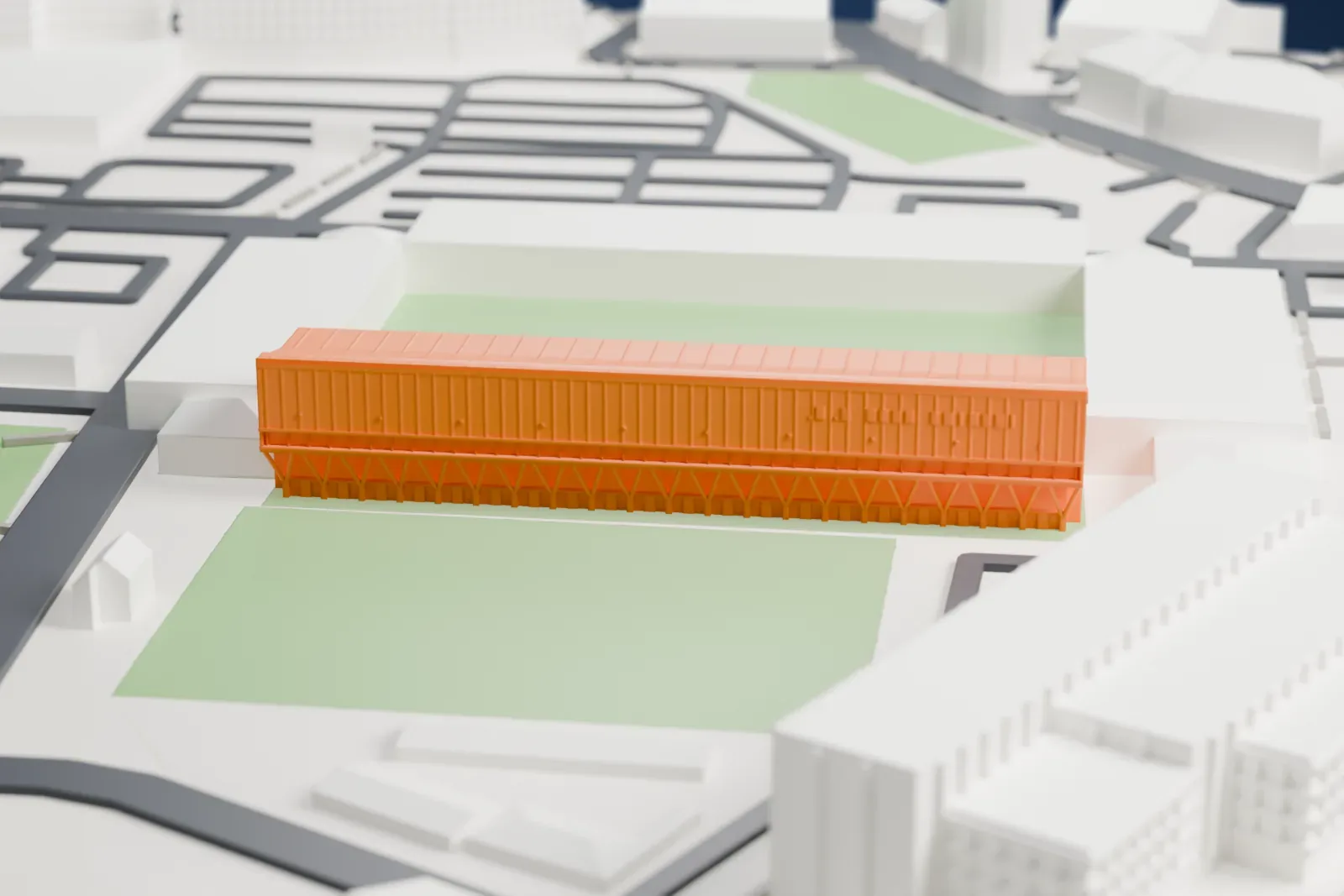 A white 3D print of the Portman Road grandstand, a tall rear wall over raking props and a roof sloping down over three tiers of seats, on a base of surrounding streets and buildings.