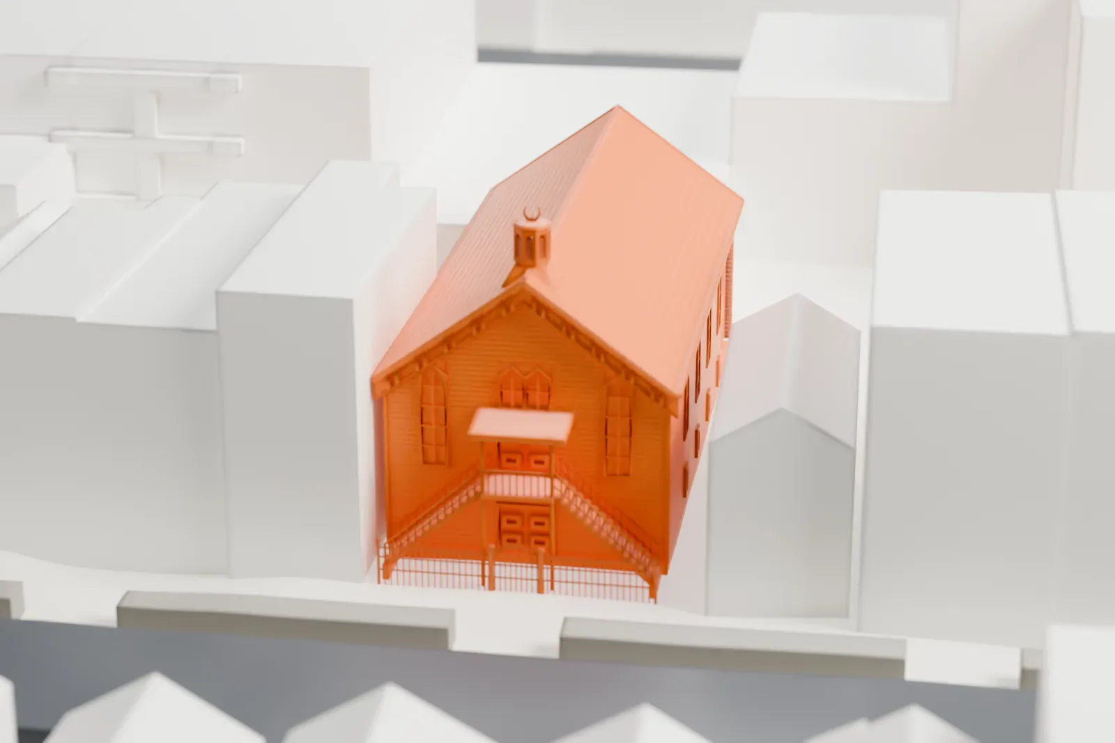 A white 3D print of the Powers Street Mosque, a small wooden building with a steep gabled roof and a front stair, among low and taller buildings.