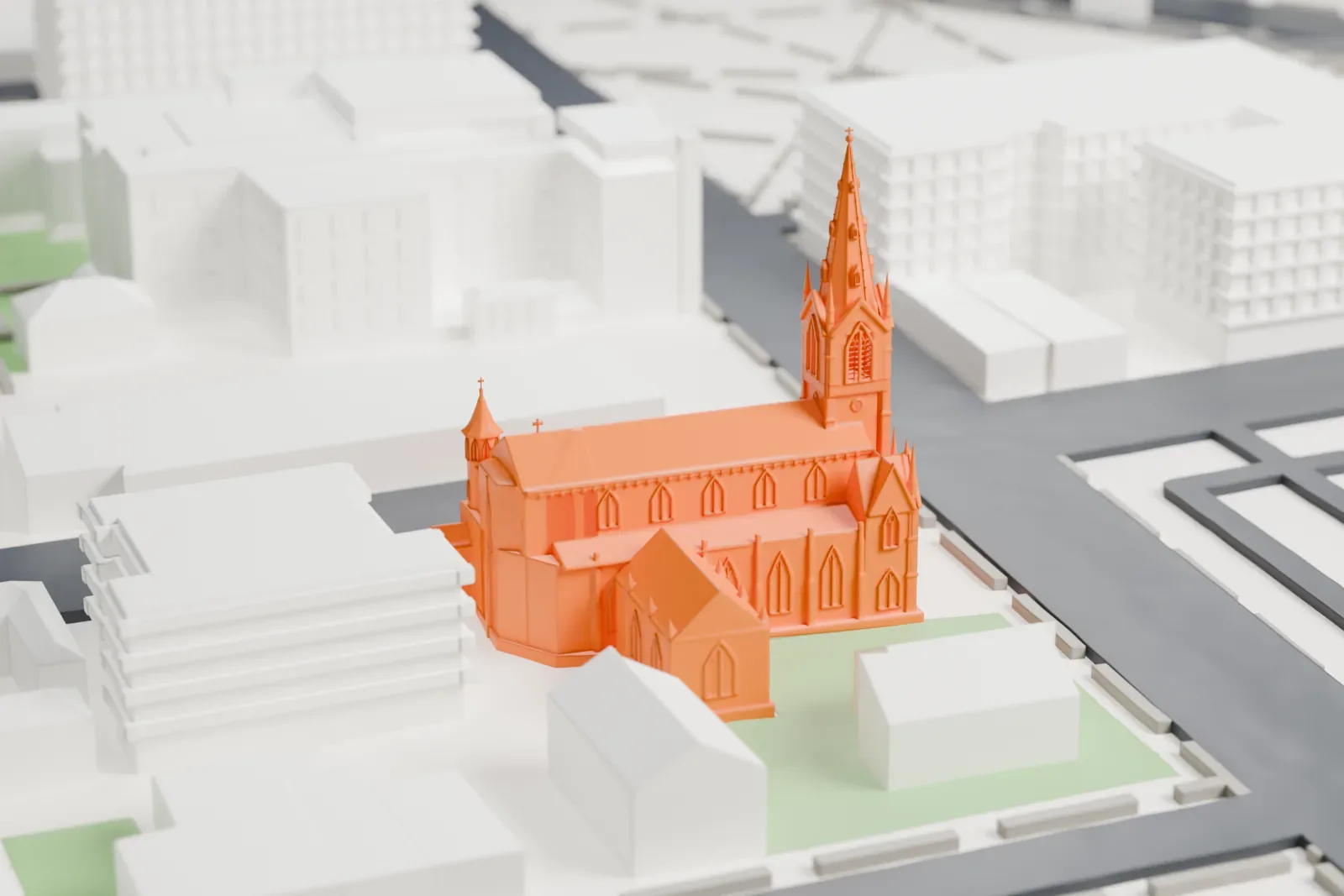 A white 3D print of the Pro-Cathedral of Saint Patrick, a Gothic-style church with a tall central spire, on a city block with wide streets and a small green lawn beside it.