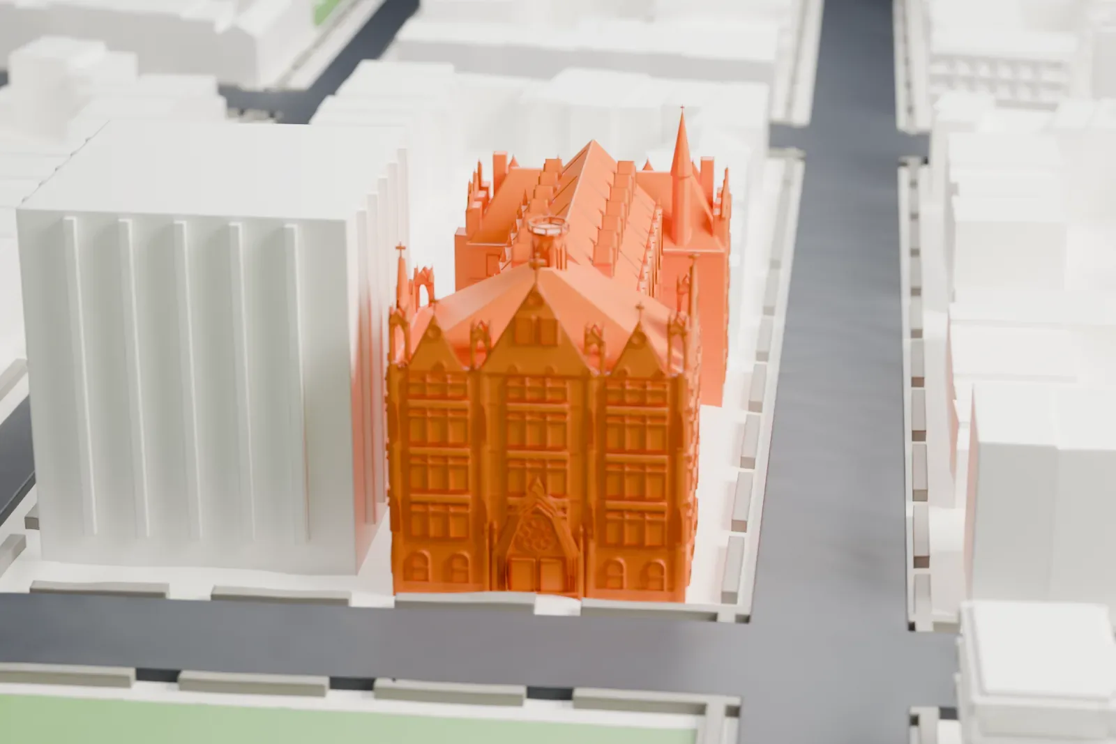 A white 3D print of Queen of All Saints Church, a Gothic-style church with steep roofs and pinnacles on a street corner beside a green open space.