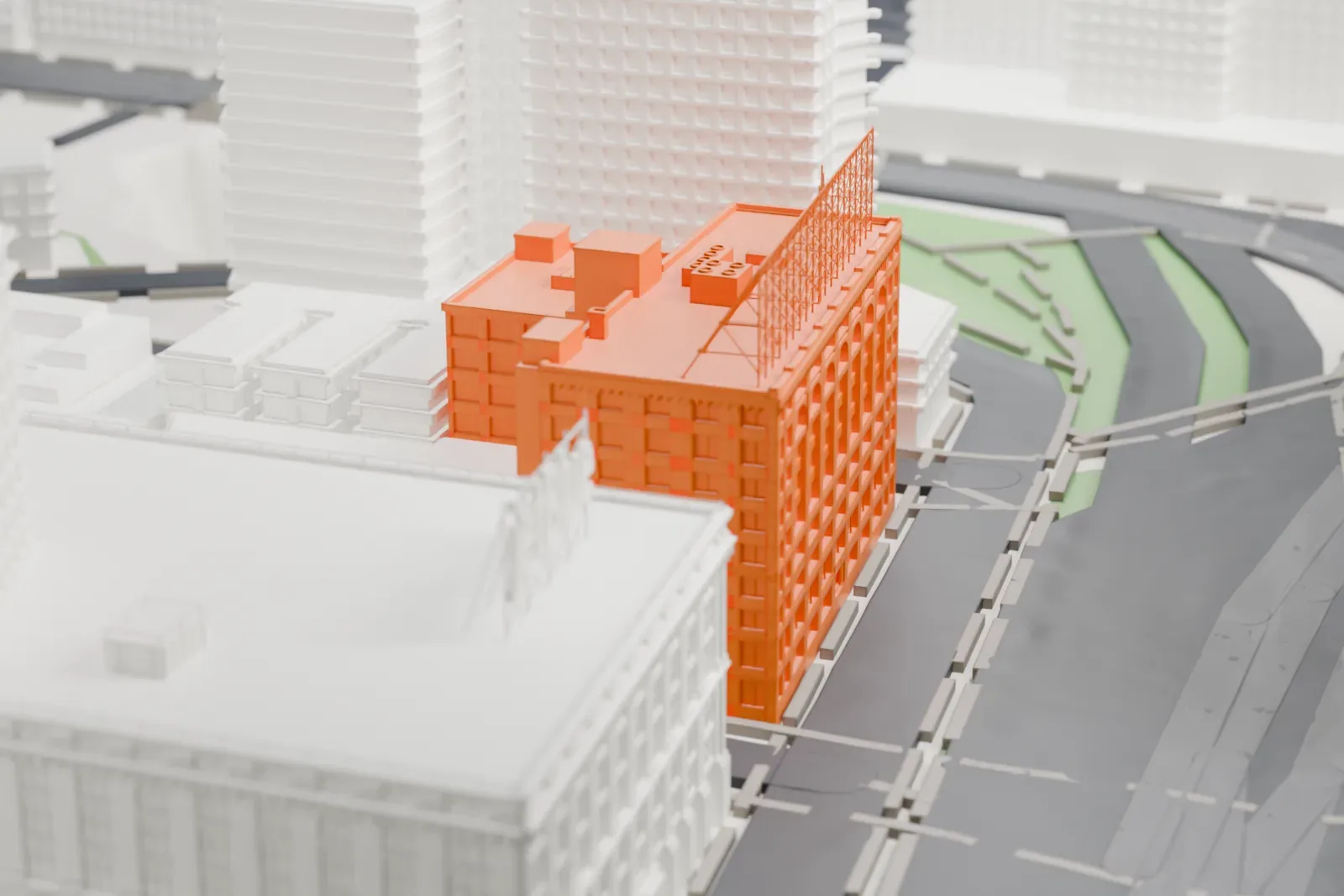 A white 3D print of the Queens Plaza Court Building, an L-shaped office building with a lattice sign frame on its roof, beside streets and taller buildings.