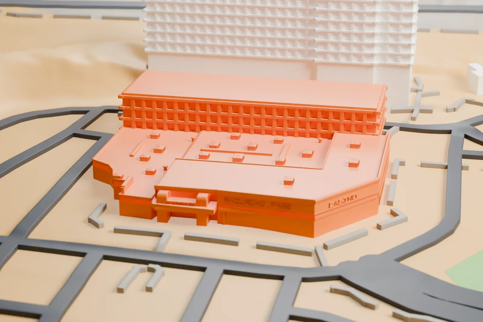 A white 3D print of Railroad Pass Casino, a low many-sided building with a flat roof dotted with small rooftop units, beside a taller hotel block and winding roads.
