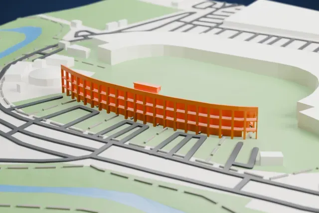 A white 3D print of the Western Tribune at Ramat Gan Stadium, a long curved stand of open seating with a low press box on the rim, among the streets and buildings around it.
