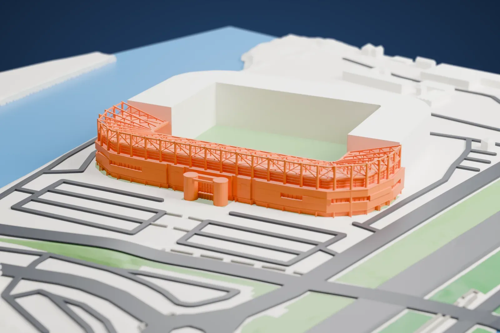 A white 3D print of the Riverside Stadium's western stands, a C-shaped run of pitched roof with white masts and trusses above it, among the streets and buildings around it.