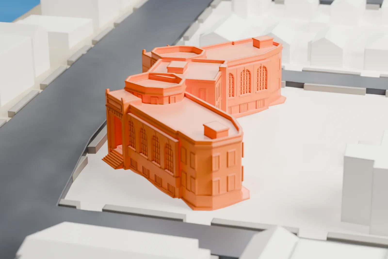 A white 3D print of Rockaway Courthouse, a V-shaped building with a columned entrance and rounded wings, on a block of low buildings and streets.