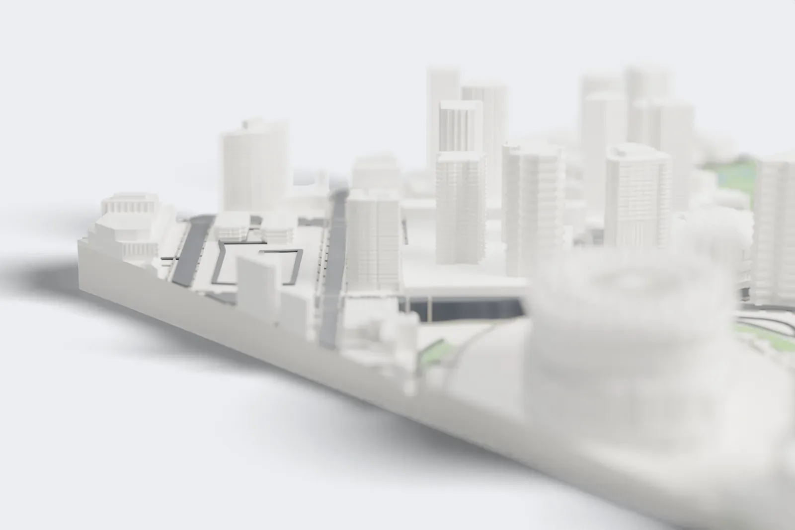 A white 3D print of Rogers Arena, an oval arena with a gently curved ribbed roof and a tall slim tower beside it, surrounded by tall buildings and wide roads.